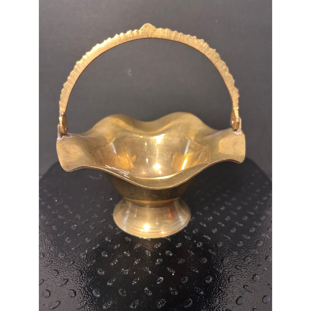 brass basket features a distinctive ruffled edge and jagged, serrated handle.